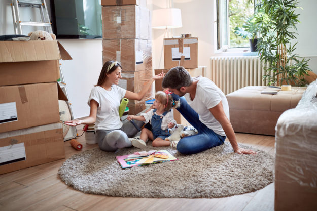 Young,Family,Of,Three,Playing,On,A,Carpet,In,New